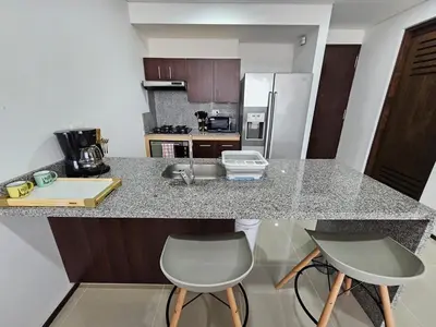 a kitchen with a counter and two chairs and a counter top at Apartamento en el Hotel Estelar in Barranquilla