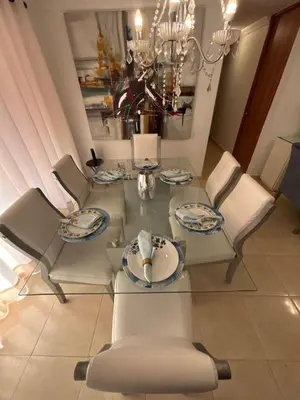 a dining room table with white chairs and a chandelier at Comfortable and Relaxing Apartment in Barranquilla