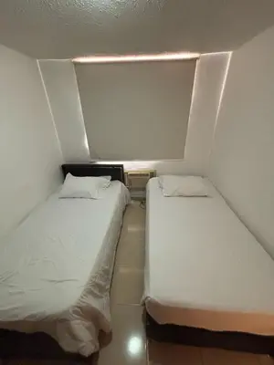 two beds in a small room with white walls at Comfortable and Relaxing Apartment in Barranquilla