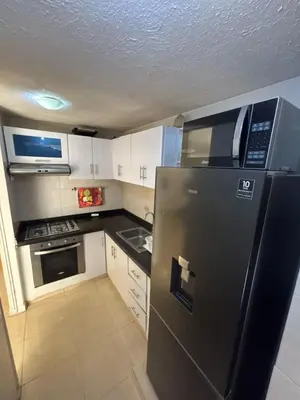 a small kitchen with a refrigerator and a microwave at Comfortable and Relaxing Apartment in Barranquilla
