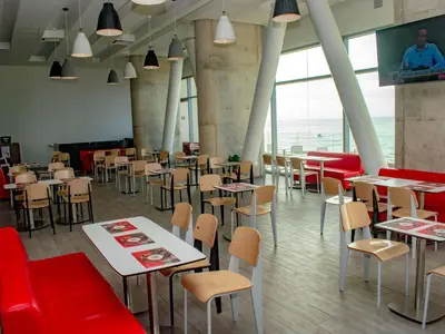 a restaurant with tables and chairs and red booths at ibis Cartagena Marbella in Cartagena de Indias