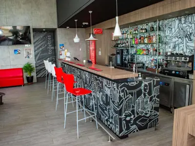 a kitchen with a bar with red chairs at ibis Cartagena Marbella in Cartagena de Indias