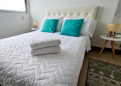 a bedroom with a white bed with blue pillows at Oceanfront apartment in Cartagena in Cartagena de Indias