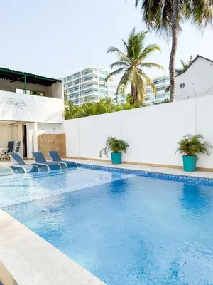 a large swimming pool with blue chairs and palm trees at Boquillas del Mar - Apartamentos in Cartagena de Indias
