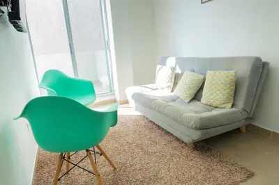 a living room with a couch and a green chair at Boquillas del Mar - Apartamentos in Cartagena de Indias