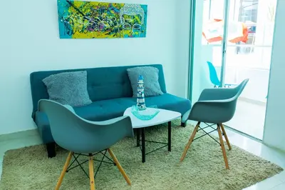 a living room with a blue couch and two chairs at Boquillas del Mar - Apartamentos in Cartagena de Indias