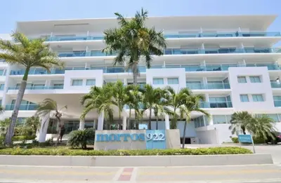 a large white building with palm trees in front of it at Apartamento en la Boquilla Cartagena in Cartagena de Indias