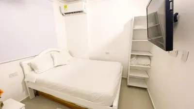 a small white room with a bed and a shelf at Apartamento Coveñas in Coveñas