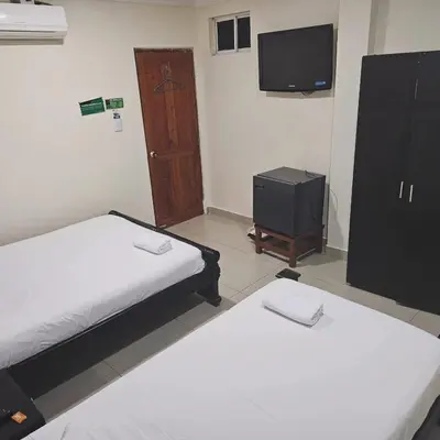 a room with two beds and a tv and a door at Hotel Barranquilla Inn in Barranquilla