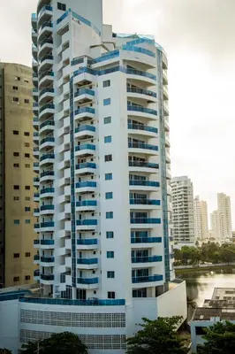 a tall white building with blue windows in a city at Apartamento Vista Mar 1604 in Cartagena de Indias