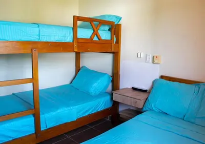 a room with two bunk beds and a bed and a table at Alojamiento Familiar #2 - La mejor playa y mar in Puerto Viejo