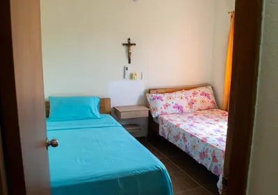 a small room with two beds and a cross on the wall at Alojamiento Familiar #2 - La mejor playa y mar in Puerto Viejo
