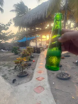 a hand holding a green bottle in front of a building at Espectacular cabaña frente al mar in Paso Nuevo