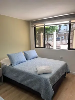 a bedroom with a bed with blue pillows and a window at Loft Deluxe - Nuevo, Acogedor, Integral, Ubicación inmejorable in Barranquilla