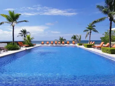 a large swimming pool with chairs and the ocean at Morros Suites Apartamentos in Cartagena de Indias
