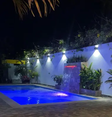 a swimming pool at night with lights on a white wall at Cabaña Julianita in Santa Veronica