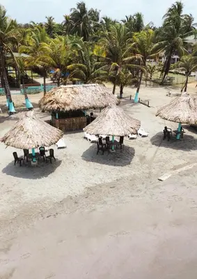 a group of tables and straw umbrellas on a beach at PalMar Ecolodge in Moñitos