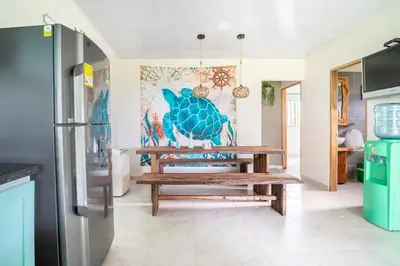 a kitchen with a table and a refrigerator at Cabaña Las Tres Palmas in San Bernardo del Viento in San Bernardo del Viento