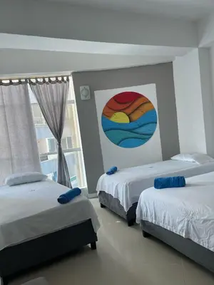 two beds in a room with a painting on the wall at Apartamento a 1 minuto de la playa in Cartagena de Indias