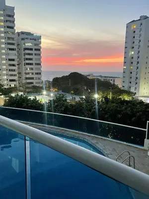 a swimming pool on the roof of a building with a sunset at Apartamento a 1 minuto de la playa in Cartagena de Indias
