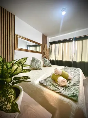 a bedroom with a large bed with pillows and a plant at Serenity Flat in Puerto Tierrabaja