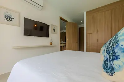 a bedroom with a bed with a tv on the wall at Mágico Oasis en Baia Kristal Vista a la Laguna 2BR in Los Arrayanes
