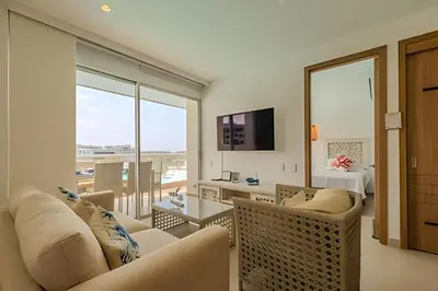 a living room with white furniture and a large window at Mágico Oasis en Baia Kristal Vista a la Laguna 2BR in Los Arrayanes