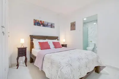 a white bedroom with a bed with red pillows at Apartamento comodo con excelente ubicacion in Cartagena de Indias