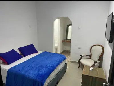 a bedroom with a bed and a chair and a television at casa real in Cartagena de Indias