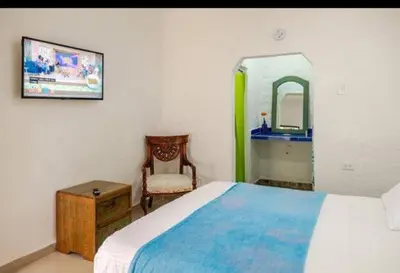 a bedroom with a bed and a chair and a mirror at casa real in Cartagena de Indias