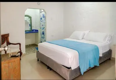 a bedroom with a bed with a blue blanket and a mirror at casa real in Cartagena de Indias