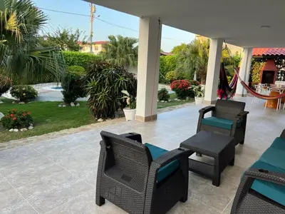 a patio with chairs and tables and palm trees at House Villa Las Marias in Juan de Acosta