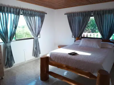 a bedroom with a bed and two large windows at House Villa Las Marias in Juan de Acosta