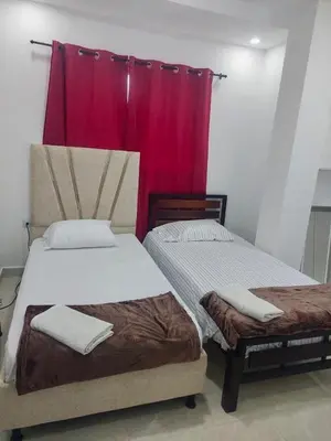 two beds in a room with a red curtain at Casa balcones del rio in Barranquilla
