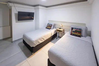 a bedroom with two beds and a tv on the wall at Cozy apartment in bocagrande in Cartagena de Indias