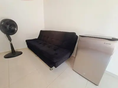 a black couch sitting in a room with a fan at Apartaestudio completo cerca Barranquilla in Galapa