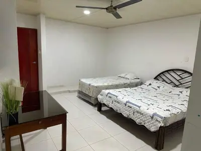 a bedroom with two beds and a table and a ceiling fan at Habitación en Santiago de Tolú in Santiago