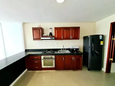 a kitchen with wooden cabinets and a black refrigerator at Apartamento con la mejor vista Cartagena in Cartagena de Indias
