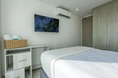 a white bedroom with a bed and a cabinet at Laurhomes Laguito Floor 33, 3HBT in Cartagena de Indias