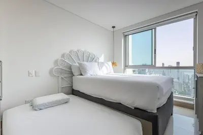 two beds in a white bedroom with a large window at Laurhomes Laguito Floor 33, 3HBT in Cartagena de Indias