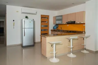 a kitchen with a refrigerator and three bar stools at Hermoso Apartamento Frente al Mar 3 Habitaciones B62 in Coveñitas