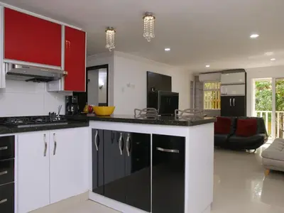 a kitchen with black and white cabinets and a living room at Historic Cartagena 2BR Apt in Cartagena de Indias