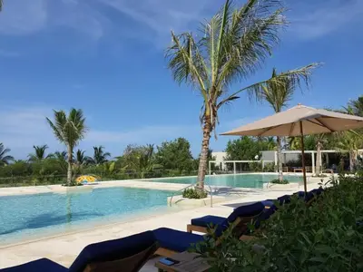 a swimming pool with chairs and an umbrella and palm trees at Morros Manzanillo 324 in Cartagena de Indias