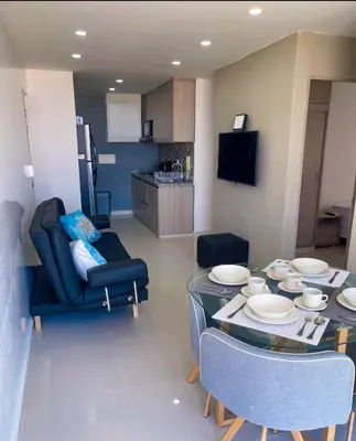 a living room with a table and chairs and a kitchen at Hermoso apto, cerca al mar in Cartagena de Indias