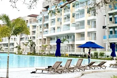 a group of chairs and an umbrella next to a swimming pool at Apartamento con piscina, playa y cerca aeropuerto de Cartagena in Cartagena de Indias