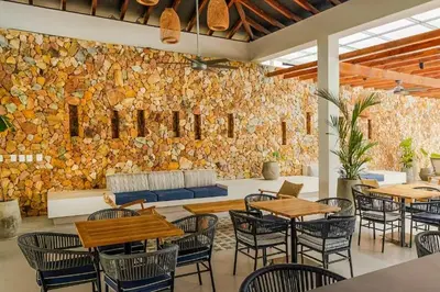a restaurant with tables and chairs and a stone wall at Apartamento con piscina, playa y cerca aeropuerto de Cartagena in Cartagena de Indias