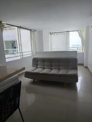 a couch sitting in a room with windows at Vista Lateral al Mar, ApartaEstudio , Cerca Hotel Hilton y Salida al Mar in Cartagena de Indias