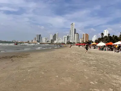 a beach with umbrellas and people walking on the beach at Vista Lateral al Mar, ApartaEstudio , Cerca Hotel Hilton y Salida al Mar in Cartagena de Indias