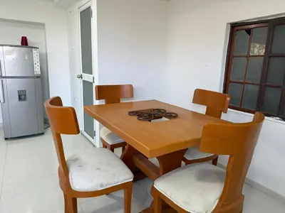 a wooden table and chairs in a kitchen with a refrigerator at Club House in Maizal