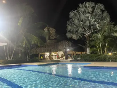 a swimming pool at night with a straw hut at Hacienda Villa Hermelina-Casa Campestre in Turbaco